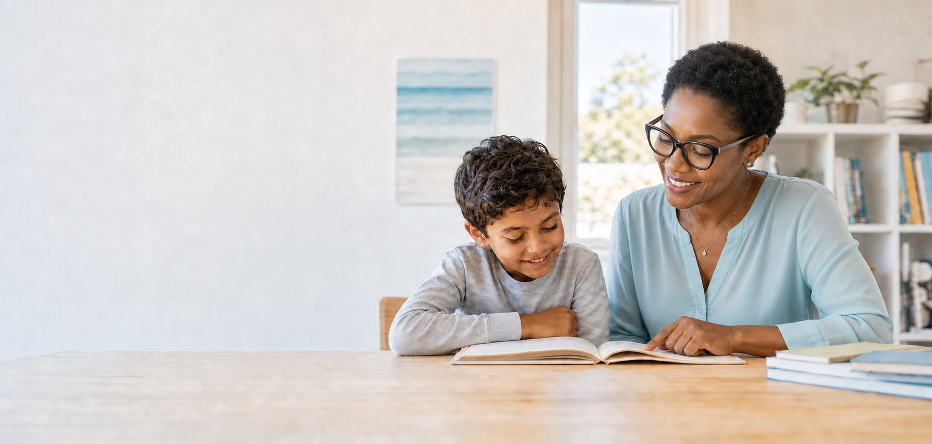 Younger African American woman tutoring a smiling child while reading together in a bright, relaxed room